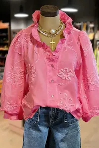 Detailed view of pink V-neck blouse with floral embroidery and ruffle puff sleeves