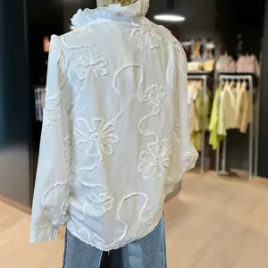 Elegant white V-neck blouse featuring intricate floral embroidery and ruffle puff sleeves.