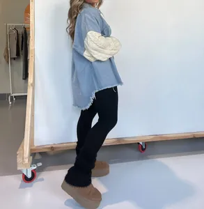 Seitenansicht der Oversize-Jeansjacke mit cremefarbenen Strickärmeln und Fransen am Saum