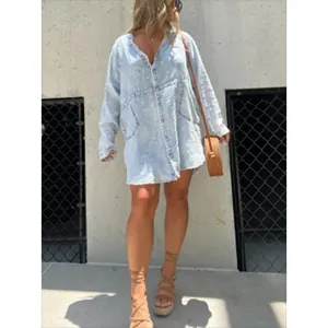 Full-body street style shot of a light blue washed V-neck denim shirt dress for women