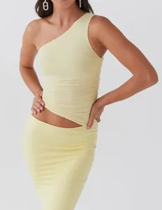 Close-up detail of light yellow one-shoulder ruched top and matching skirt set for women