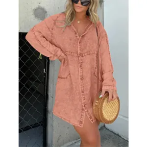 Detailed view of a washed coral pink denim shirt dress featuring raw edge seams and loose fit.
