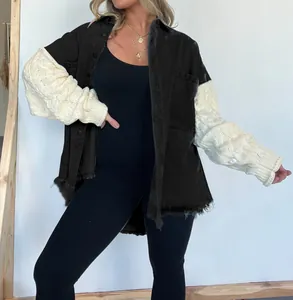 Detailansicht der schwarzen Jeansjacke mit weißen Strickärmeln und offenem Saumrand.
