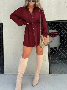 Modischer burgunderroter Langarm-Hemd-Jumpsuit mit Taillenbindung, getragen von einem Model.