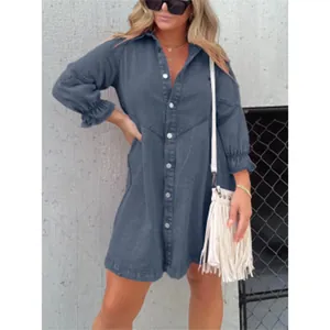 Dettaglio di un abito a camicia in denim blu lavato con maniche a lanterna e bottoni.