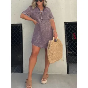 Détail d'une robe en jean violette délavée avec col chemise et ourlet à franges