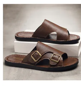 Detail view of brown leather men's slides with adjustable metal buckles on a white prop.