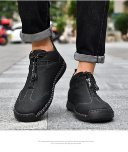 Close-up detail of black handmade stitched leather boots with front zipper and toggle closure.