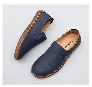 Detailed view of hand-stitched blue men's loafers with orange contrast thread