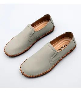 Detailed macro shot of men's hand-stitched grey leather loafers with soft soles and orange trim