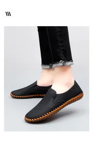Detailed view of men's black loafers with orange hand-stitched details and soft soles