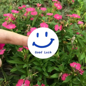 Détail d'un autocollant rond blanc arborant un smiley bleu et le texte Good Luck