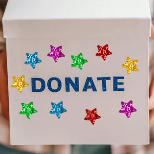 Close-up of colorful holographic star stickers applied to a white gift box surface.