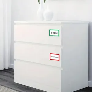Dettaglio delle etichette colorate su una cassettiera bianca per l'organizzazione