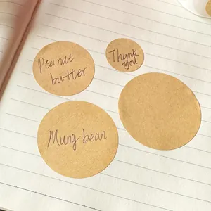 Close-up van ronde kraftpapier stickers met handgeschreven labels op een gelinieerd schrift