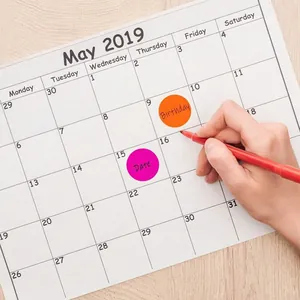 Gros plan d'autocollants ronds colorés utilisés pour marquer des dates sur calendrier