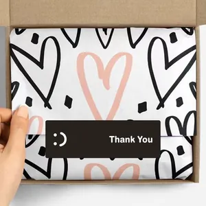 Close-up view of a rectangular black Thank You sticker with a smiley face on a gift box