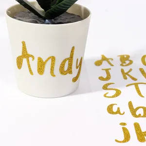 Primer plano de letras adhesivas con purpurina dorada en una maceta blanca