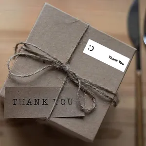 Close-up view of a white rectangular Thank You sticker with smiley face on gift box