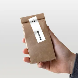 Detail view of a white rectangular 'Thank You' smiley sticker sealing a brown paper bag.
