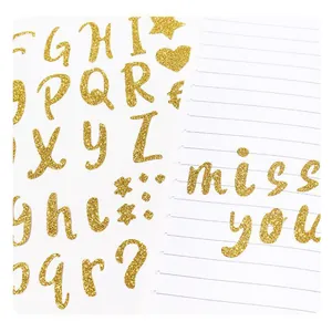 Primer plano de pegatinas de alfabeto con purpurina dorada con el texto 'miss you' en papel rayado.