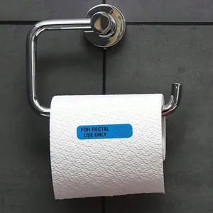 Funny blue 'For Rectal Use Only' prank adhesive sticker on a white toilet paper roll.