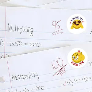 Primer plano de pegatinas de recompensa emoji amarillas con texto motivador en un cuaderno