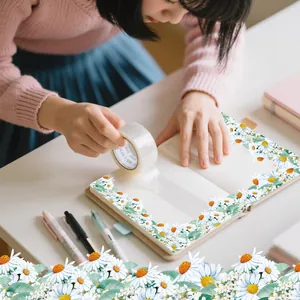 Detailed view of white daisy floral PET tape being applied to a journal for DIY crafting