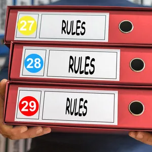 Primer plano de etiquetas numéricas redondas de colores 27, 28 y 29 en carpetas rojas