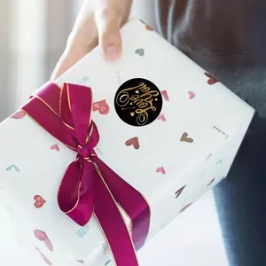 Macro detail of a black circular 'Love you' gold foil sticker on a heart gift box