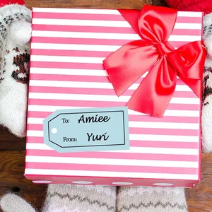 Detail of a blue personalized 'To' and 'From' gift tag sticker on a striped box