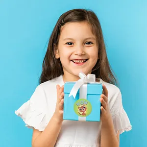 Close-up of a child holding a gift box featuring a cute cartoon reward sticker