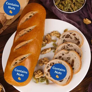 Detail shot of Contains Nuts warning stickers applied on fresh bread slices and loaf.
