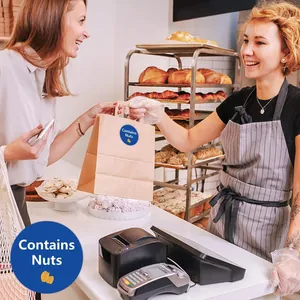 Blue round 'Contains Nuts' food warning labels sealing a brown paper bakery bag