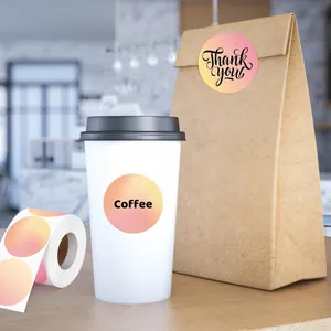 Detalle de pegatinas circulares con degradado rosa y amarillo en una taza de café