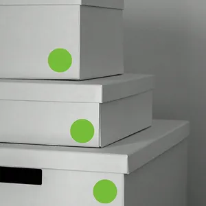 Autocollants ronds verts sur boîtes blanches pour l'organisation et l'étiquetage