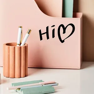 Gros plan d'un autocollant noir Hi heart appliqué sur un organiseur de bureau rose