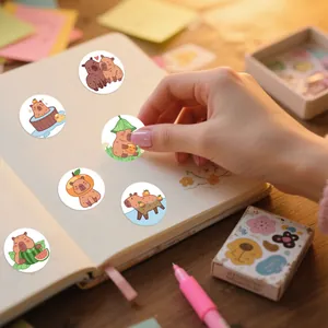 Nahaufnahme von niedlichen Cartoon-Capybara-PVC-Stickern, die auf ein Notizbuch geklebt werden