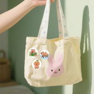 Nahaufnahme von süßen Capybara-PVC-Aufklebern auf einer cremefarbenen Stofftasche