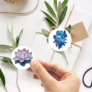 Vue détaillée d'autocollants scellés floraux sur une boîte cadeau blanche avec feuilles