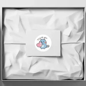 Detail of a cute blue dinosaur thank you sticker placed on a white gift card inside a box