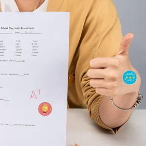 Pegatinas de recompensa para niños mostradas en la mano y en un examen escolar calificado