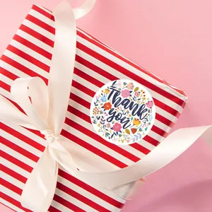 Gros plan d'un autocollant fleuri Thank You sur une boîte cadeau à rayures
