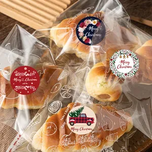 Close-up of Christmas stickers sealing bakery bags with croissants on wooden table.