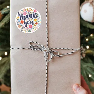 Vue détaillée d'un autocollant fleuri 'Thank you' sur une boîte cadeau en papier kraft