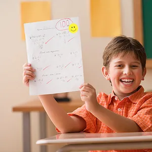 Detail of a yellow smiley face reward sticker on a student's high-scoring test paper