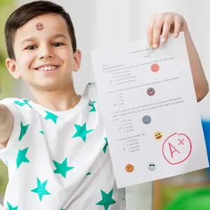 Cute colorful mixed smiley face stickers displayed on a child's school test paper