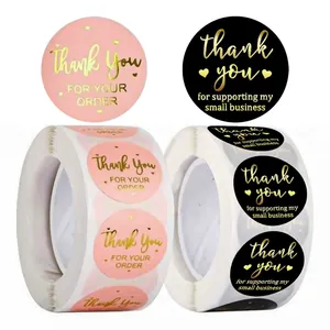 Close-up of pink and black gold foil thank you stickers for small business packaging