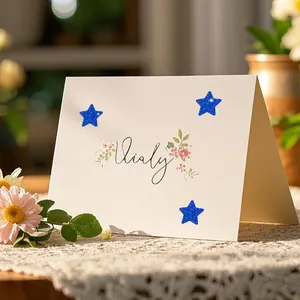 Detailed close-up view of blue glittery star stickers applied to a white greeting card.