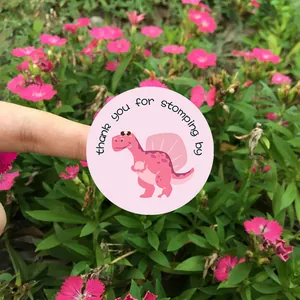 Detailed view of pink cartoon dinosaur sealing sticker set against garden flowers